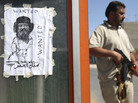 A rebel fighter patrolled near a homemade wanted of Moammar Gadhafi at a checkpoint in Tripoli, Libya, on Tuesday. A rebel fighter patrolled near a homemade wanted of Moammar Gadhafi at a checkpoint in Tripoli, Libya, on Tuesday.
