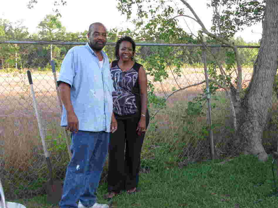 Anthony and Eunice Crane stand in their backyard in Gulfport, Miss. The new port access road will be built behind their fence. Their home used to back to other homes.