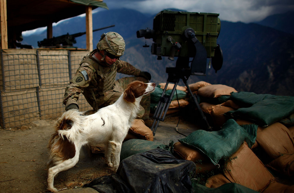 Pfc. Robert Hicks pets Cookie, a local Afghan dog that has adopted the men who stay at Observation Post Mustang.