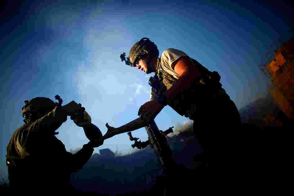 Pfc. Darren Jaworski (left) hands Spc. Aaron Frederick a mortar round while under fire.