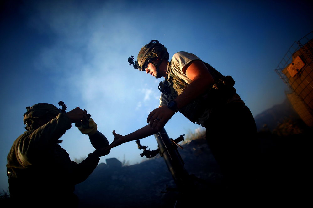 Pfc. Darren Jaworski (left) hands Spc. Aaron Frederick a mortar round while under fire.