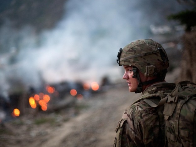 Army Pfc. Brayden Panttaja, 23, of Moscow, Idaho, walks past a pile of burning garbage while descending from a hilltop observation post at Combat Outpost Monti in Kunar province, Afghanistan, on Tuesday.