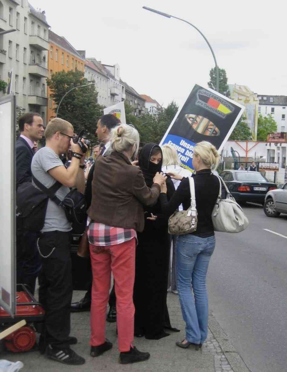 Pro Deutschland supporters carry signs depicting a women in a niqab with jailhouse bars in front of the gap left for the eyes. Pro Deutschland supporters carry signs depicting a women in a niqab with jailhouse bars in front of the gap left for the eyes.