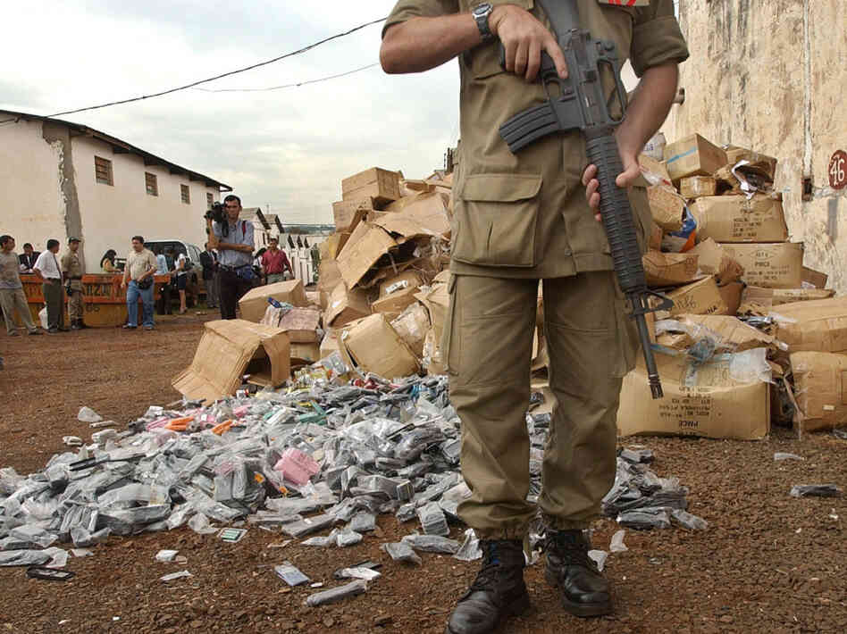 A police officer guards a stash of fake merchandise in Ciudad del Este,  Paraguay, the smuggler-ridden border town were Rotella sets part of his novel.
