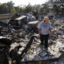 Hillary Polly looks through the family belongings as Thomas Polly tries to pry open a fireproof gun safe with his father Louie Polly in the background amongst the rubble of their burned house near Bastrop, Texas.