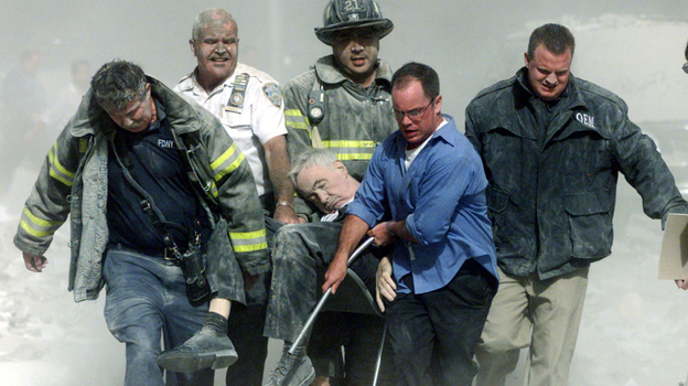 A mortally injured Father Mychal Judge is carried out of the World Trade Center by first responders, including Bill Cosgrove (in white shirt). Cosgrove says, "everybody you see in that picture was saved" from the North Tower's collapse, moments later.