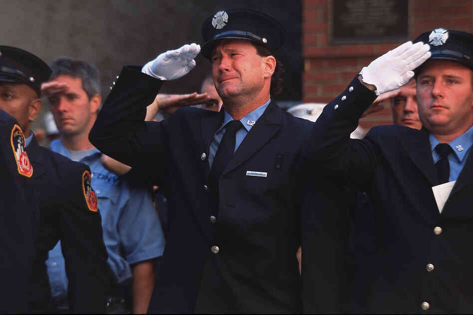 New York City firemen cry at the funeral of New York Fire Department chaplain Mychal Judge, who died administering last rites to a fallen firefighter. 