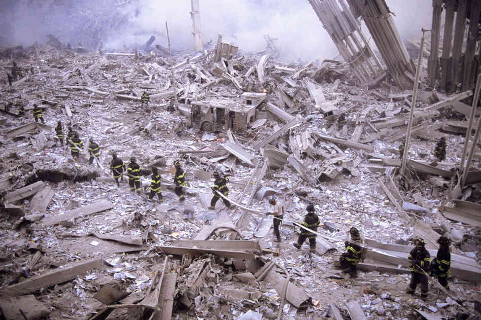 Firefighters carry hose across wreckage after collapse of the World Trade Center's twin towers. 