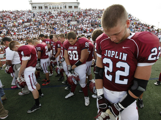 Football players observe a moment of silence before Joplin High School's home opener Saturday. The Missouri city has tried to recover from billions of dollars in damage from a tornado in May.