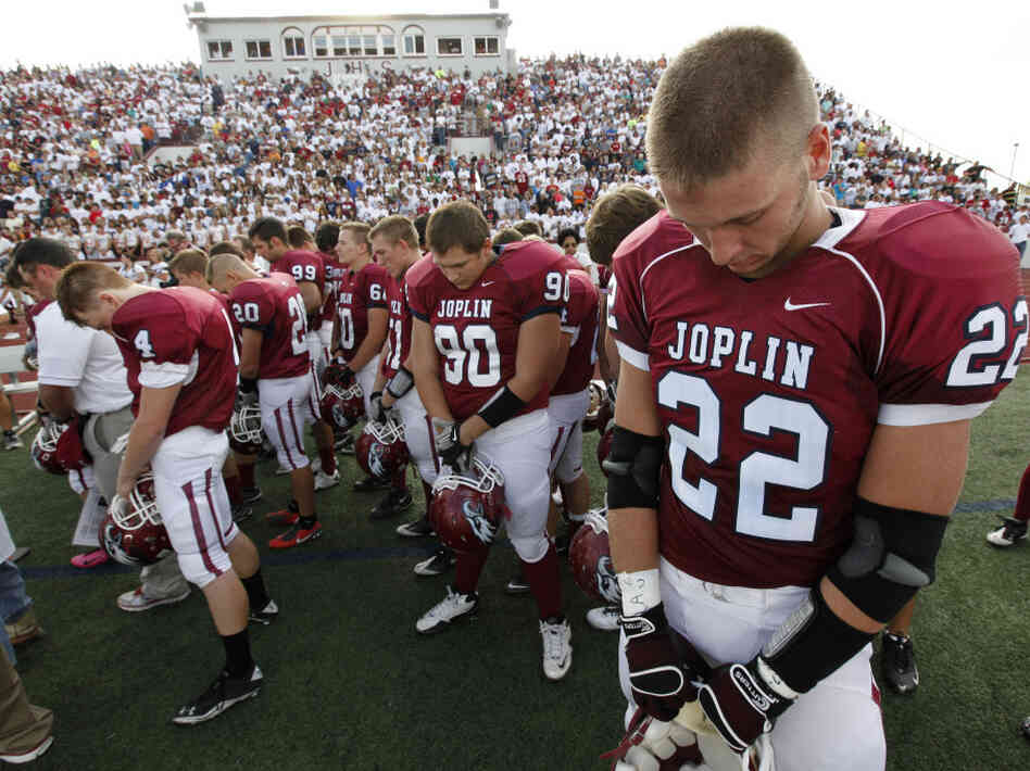 Football players observe a moment of silence before Joplin High School's home opener Saturday. The Missouri city has tried to recover from billions of dollars in damage from a tornado in May.
