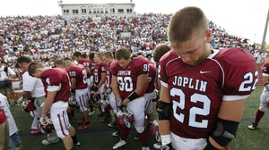 Football players observe a moment of silence before Joplin High School's home opener Saturday. The Missouri city has tried to recover from billions of dollars in damage from a tornado in May.