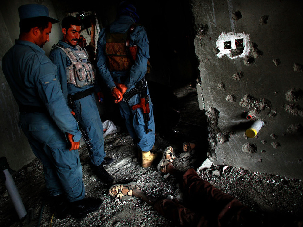 Afghan Security personnel stand above the body of one attacker, on the 10th floor of the building in Kabul from which RPGs and other weapons were fired.
