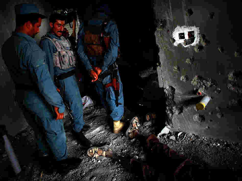 Afghan Security personnel stand above the body of one attacker, on the 10th floor of the building in Kabul from which RPGs and other weapons were fired.