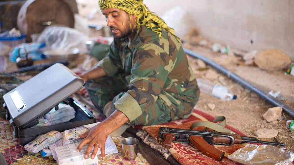 A fighter loyal to the Transitional National Council sits with money that has been donated to pay fighters at a checkpoint outside Bani Walid, Libya, on Monday. It was widely feared that ousted leader Moammar Gadhafi and his supporters spirited away much of the country's wealth. But those fears have yet to materialize, as Libya's central bank holdings appear to remain largely intact.