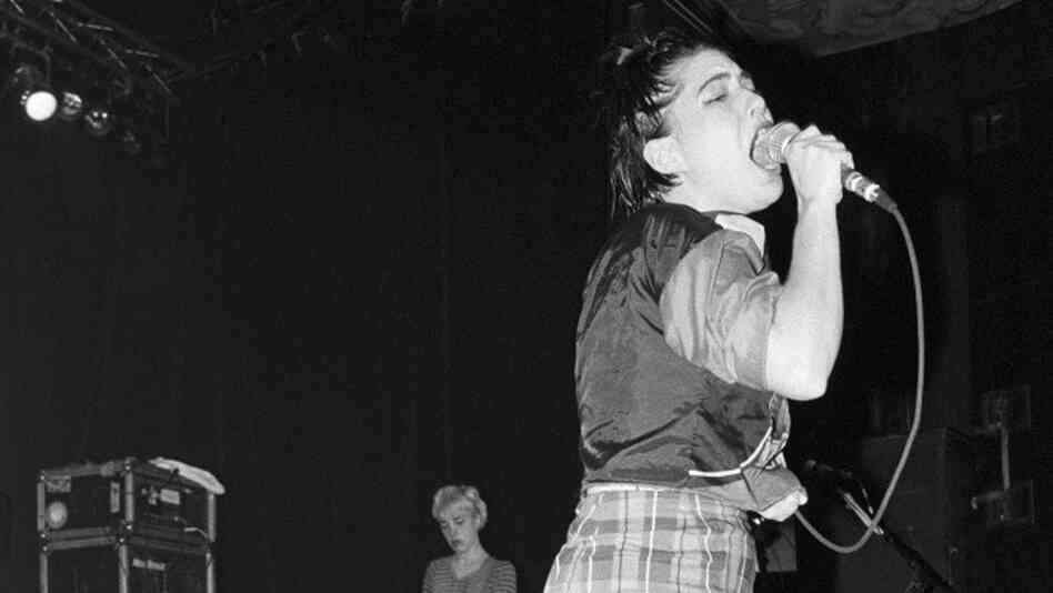 Bikini Kill onstage in New York City in 1994. Kathleen Hanna singing,  Kathi Wilcox on bass behind her.