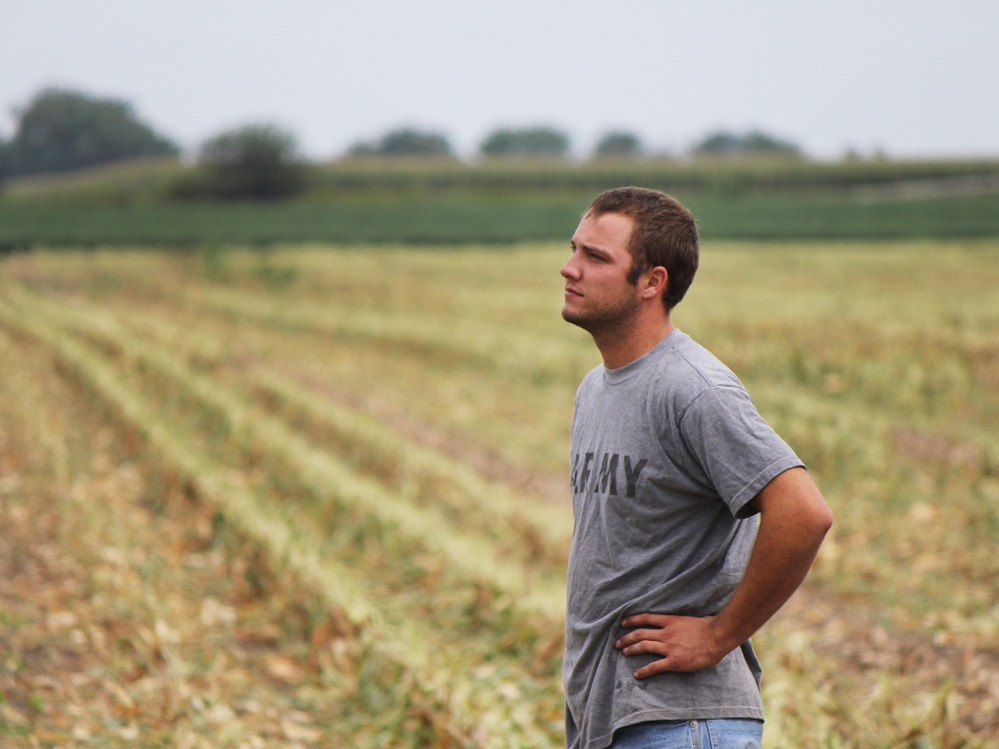 Austin Bruns stands on land owned by a contractor for Monsanto, an agriculture corporation. Bruns helps with seed corn production there, and also rents 150 acres elsewhere.