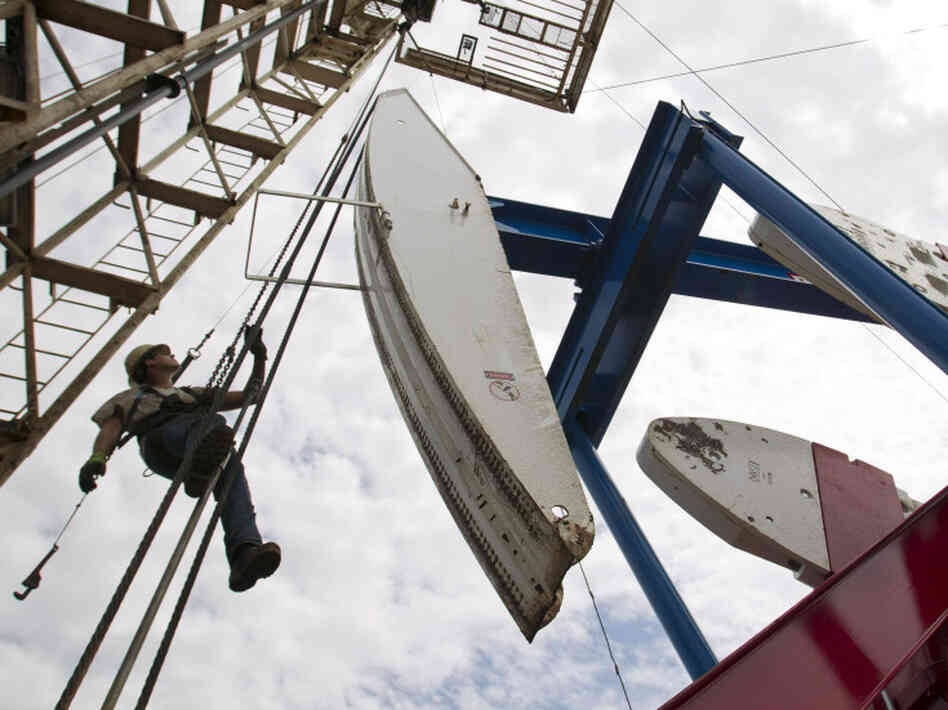 Ben Shaw hangs from an oil derrick outside Williston, ND, in July 2011. Williston's mayor, Ward Koeser, estimates that the town has between 2,000 and 3,000 job openings for oil workers.