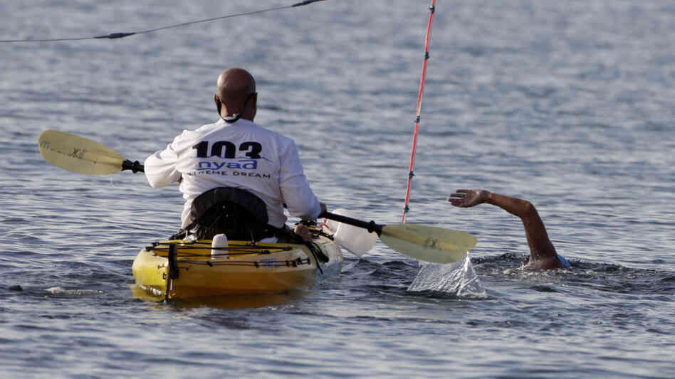 A member of Diana Nyad's support team accompanies her as she begins her swim from Cuba to Florida at the Hemingway Marina in Havana, Cuba on Friday.