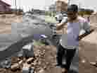 A man stands in a sewage-filled street in Fallujah in 2010. The Fallujah wastewater treatment system was left unfinished more than four years past the initial deadline. The sewage facility is among hundreds of projects funded by U.S. taxpayers that remain abandoned or incomplete, wasting more than $5 billion, according to auditors.