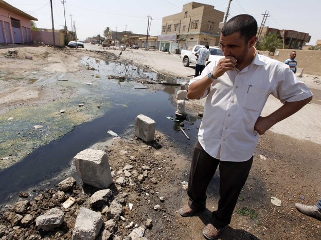 A man stands in a sewage-filled street in Fallujah in 2010. The Fallujah wastewater treatment system was left unfinished more than four years past the initial deadline. The sewage facility is among hundreds of projects funded by U.S. taxpayers that remain abandoned or incomplete, wasting more than $5 billion, according to auditors.