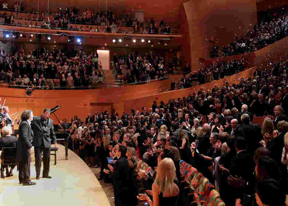 The audience greets the 'Rhapsody in Blue' performance with cheers as confetti falls.