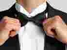 An uptight man straightens his bow tie.