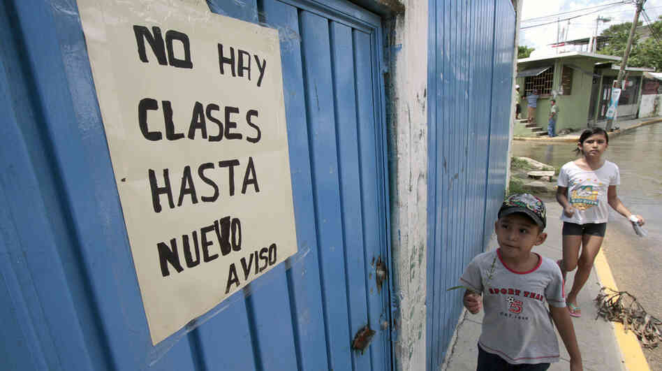 In Acapulco, Mexico, teachers are out on strike at more than a hundred schools because of spiraling violence related to the country's drug war. Here, a child looks at a sign announcing the closure of a school in Acapulco, Sept. 1.