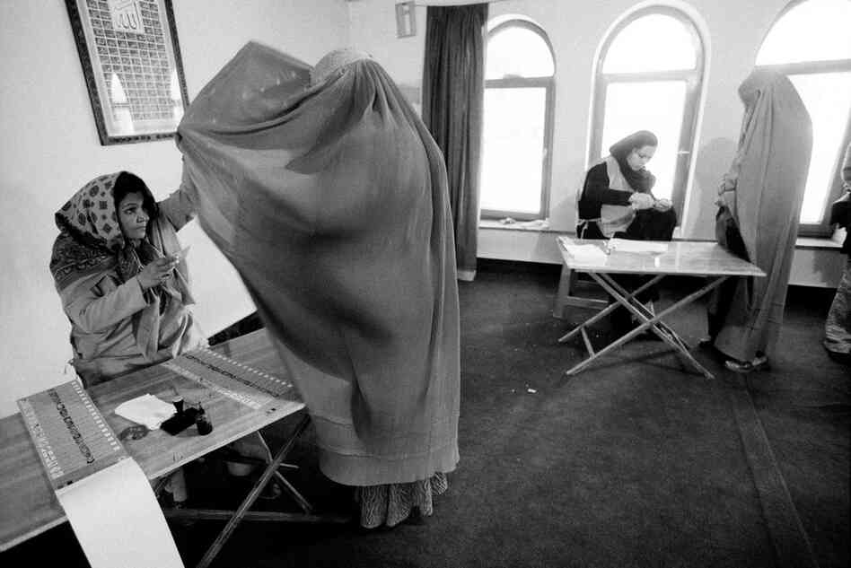 An election worker checks the identity of a voter at a polling station during Afghanistan's presidential election, Kabul, 2004.