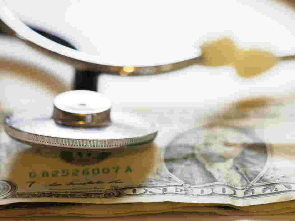 A stethoscope rests on a dollar bill. A stethoscope rests on a dollar bill.