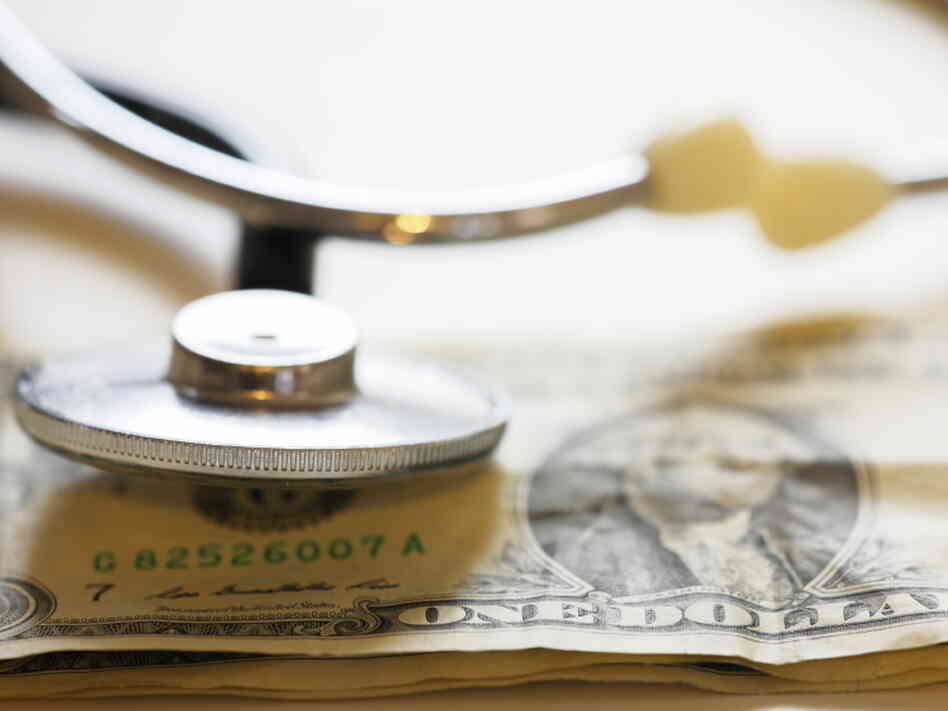 A stethoscope rests on a dollar bill. A stethoscope rests on a dollar bill.