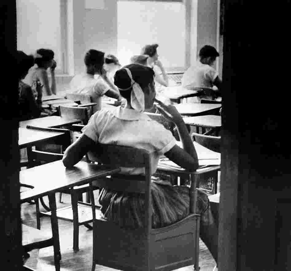 An unidentified African American student sits inside a classroom at Clinton High School, which was newly integrated when this photo was taken on Aug. 31, 1956. She sits in a rear seat near the door and is separated by empty desks as the white children sit at the far side of the room.
