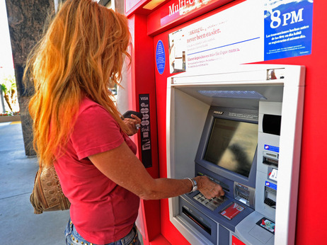 A customer uses a Bank of America ATM in Los Angeles. The bank plans to start charging a $5 monthly fee for customers who use their debit card for purchases starting early in 2012. ATM transactions would still be free.