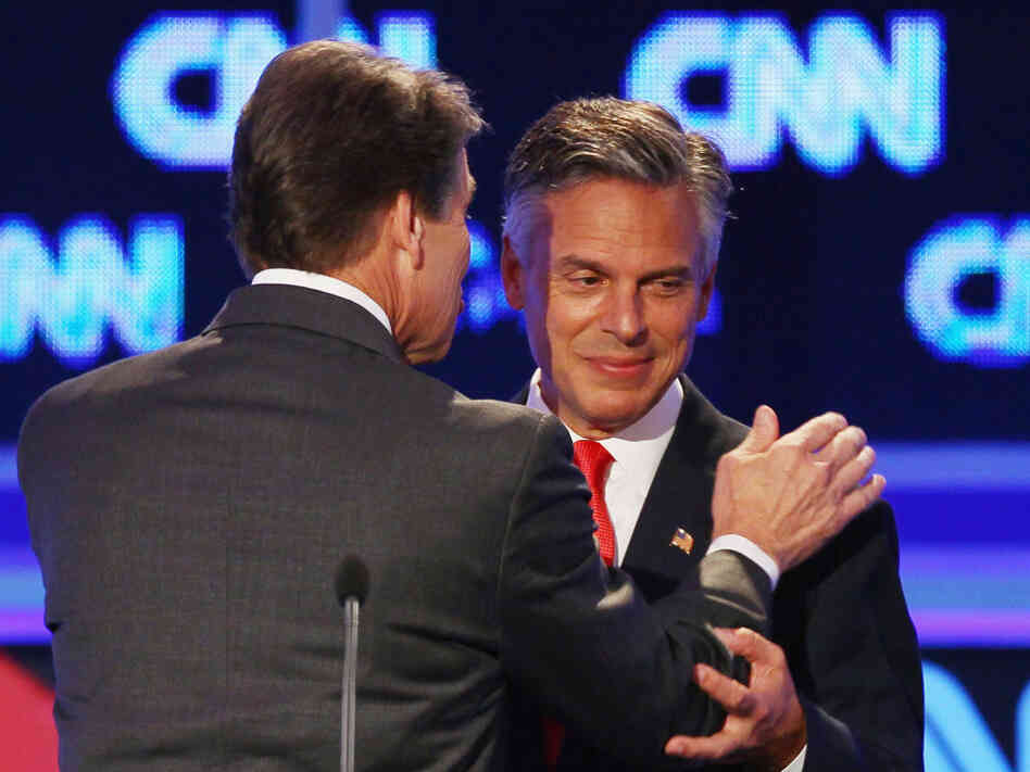 Former Utah Gov. Jon Huntsman (right) and Texas Gov. Rick Perry confer during a break in the Sept. 12 presidential debate in Tampa. Huntsman first objected to Perry's use of the word "treasonous" then later used it himself. 