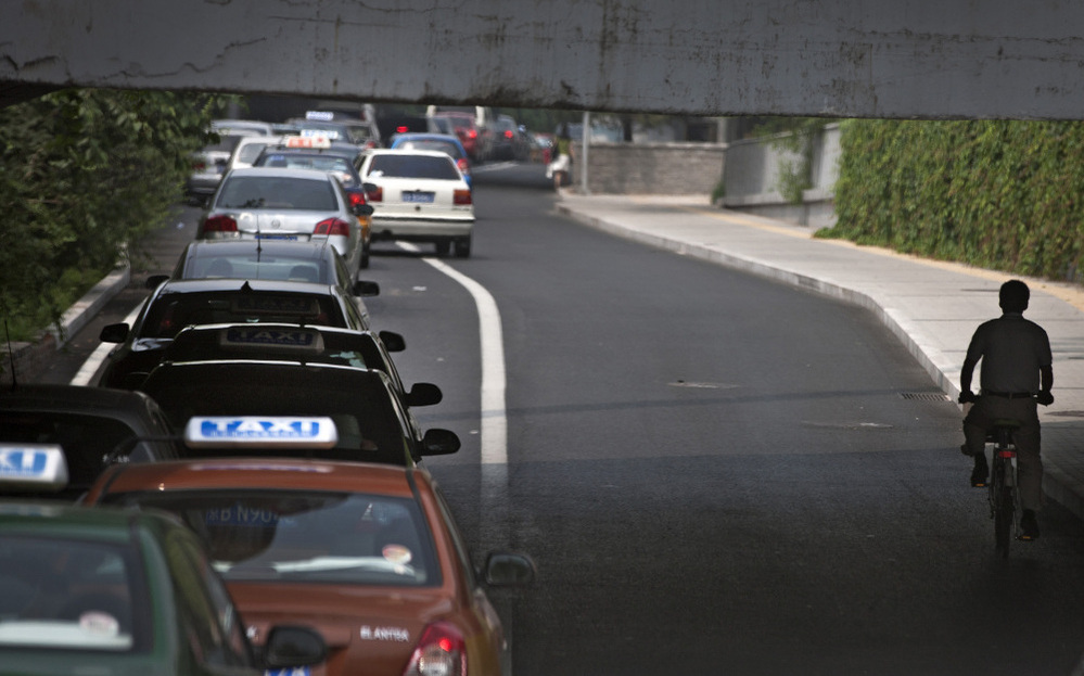 A cyclist in passes a line of cars during rush hour in Beijing. While auto sales remain strong in China, the country is also reportedly experiencing a resurgence of interest in bicycles.