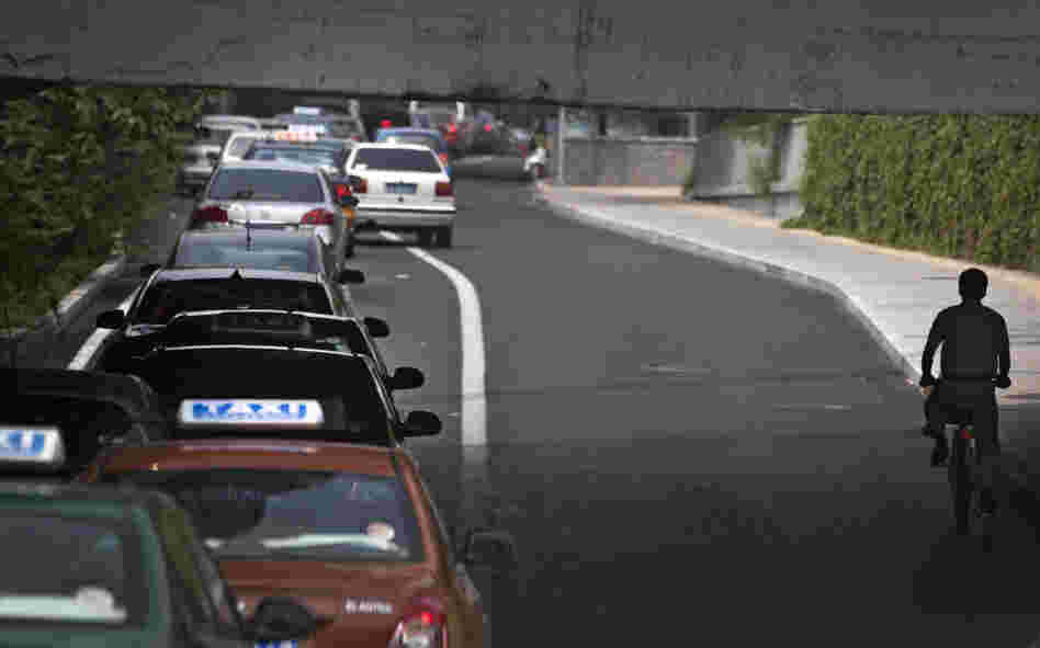 A cyclist in passes a line of cars during rush hour in Beijing. While auto sales remain strong in China, the country is also reportedly experiencing a resurgence of interest in bicycles.