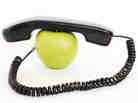 An apple with a phone handset on top of it.
