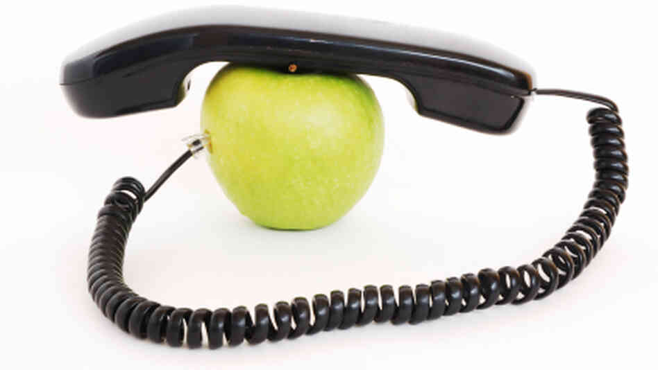 An apple with a phone handset on top of it. An apple with a phone handset on top of it.