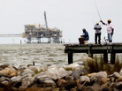 Men fish off a pier at a jetty in Dauphin Island, Ala., with oil rigs in the background. The U.S. government is changing how it regulates drilling platforms. Men fish off a pier at a jetty in Dauphin Island, Ala., with oil rigs in the background. The U.S. government is changing how it regulates drilling platforms.
