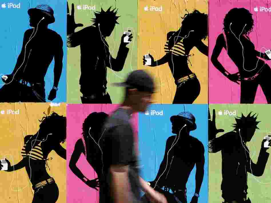 A pedestrian passes a wall covered with Apple iPod advertisements July 14, 2005 in San Francisco.