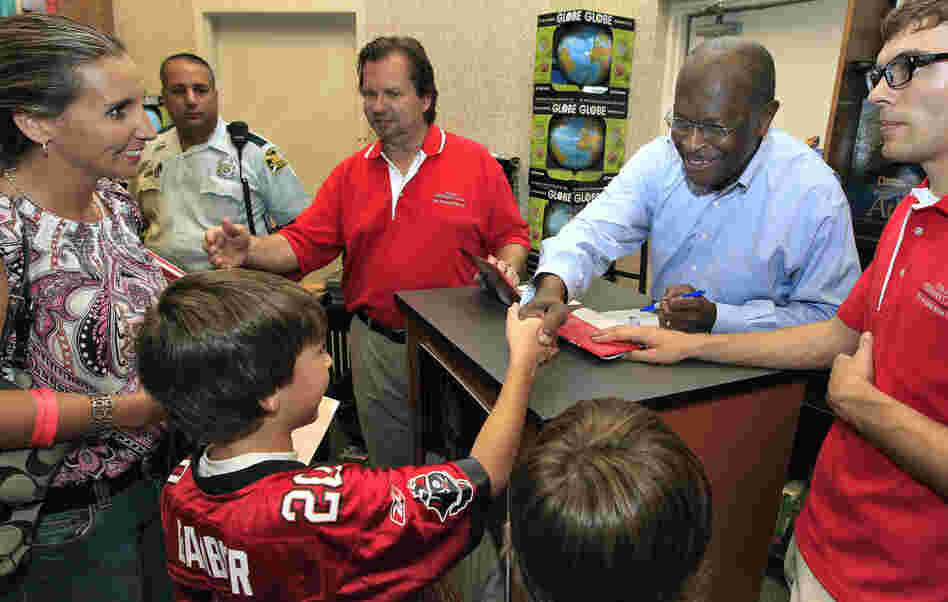 Herman Cain shakes hands with a family at a Petersburg, Fla. book signing, Wednesday, Oct. 5, 2011.