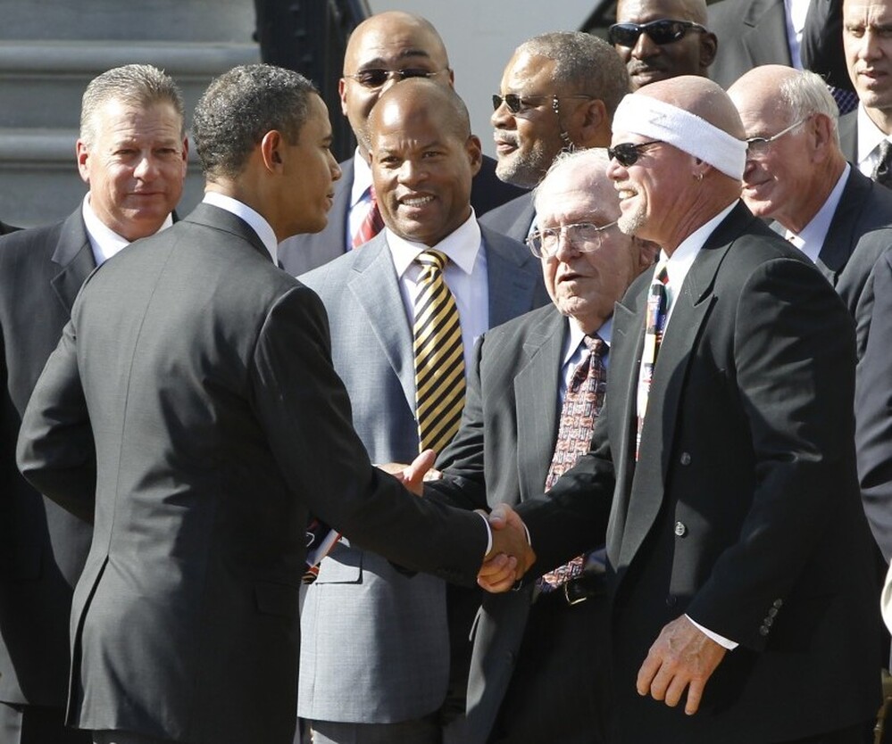President Barack Obama shakes hands with former Chicago Bears quarterback Jim McMahon as he hosts the 1985 Chicago Bears football team at the White House. The visit was a make-up trip for the Super Bowl XX champions, whose original reception was cancelled in 1986.