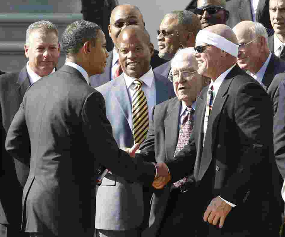 President Barack Obama shakes hands with former Chicago Bears quarterback Jim McMahon as he hosts the 1985 Chicago Bears football team at the White House. The visit was a make-up trip for the Super Bowl XX champions, whose original reception was cancelled in 1986.