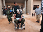 On a morning of fierce street fighting, a wounded man is wheeled into a field hospital outside Sirte. The city was rocked by explosions, and Libyan National Transitional Council fighters were targeted by pro-Gadhafi snipers. On a morning of fierce street fighting, a wounded man is wheeled into a field hospital outside Sirte. The city was rocked by explosions, and Libyan National Transitional Council fighters were targeted by pro-Gadhafi snipers.