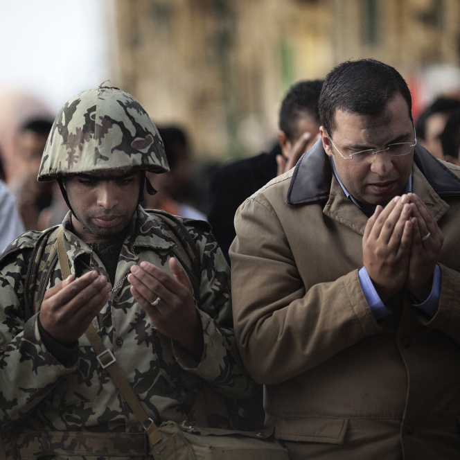 Jan. 30, 2011: In Cairo's Tahrir Square, an Egyptian army soldier joins a crowd of Muslim demonstrators to say prayers. 