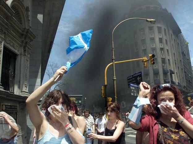 Protesters in Argentina in 2001 wave national flags as they walk through tear gas and smoke from burning street fires set by demonstrators during the country's financial crisis.