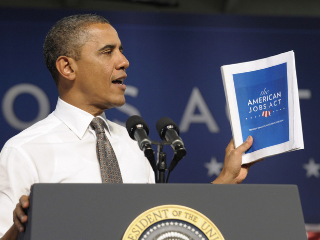 President Obama holds up a copy of his jobs bill as he speaks at Eastfield College in Mesquite, Texas. Obama is challenging a divided Congress to unite behind the bill or get ready to be run "out of town" by angry voters. 