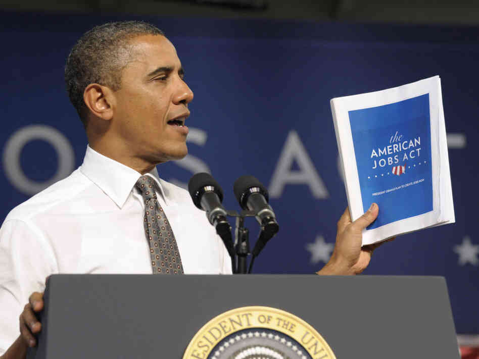 President Obama holds up a copy of his jobs bill as he speaks at Eastfield College in Mesquite, Texas. Obama is challenging a divided Congress to unite behind the bill or get ready to be run "out of town" by angry voters. 