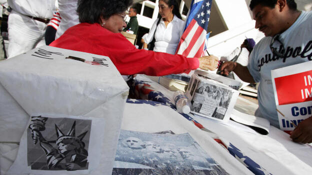 An immigrant signs a voter registration information card at a booth set up at a rally in downtown Miami in 2007. If a new law is upheld, the time period groups have to turn in new voter registrations will be reduced from 10 days to two.