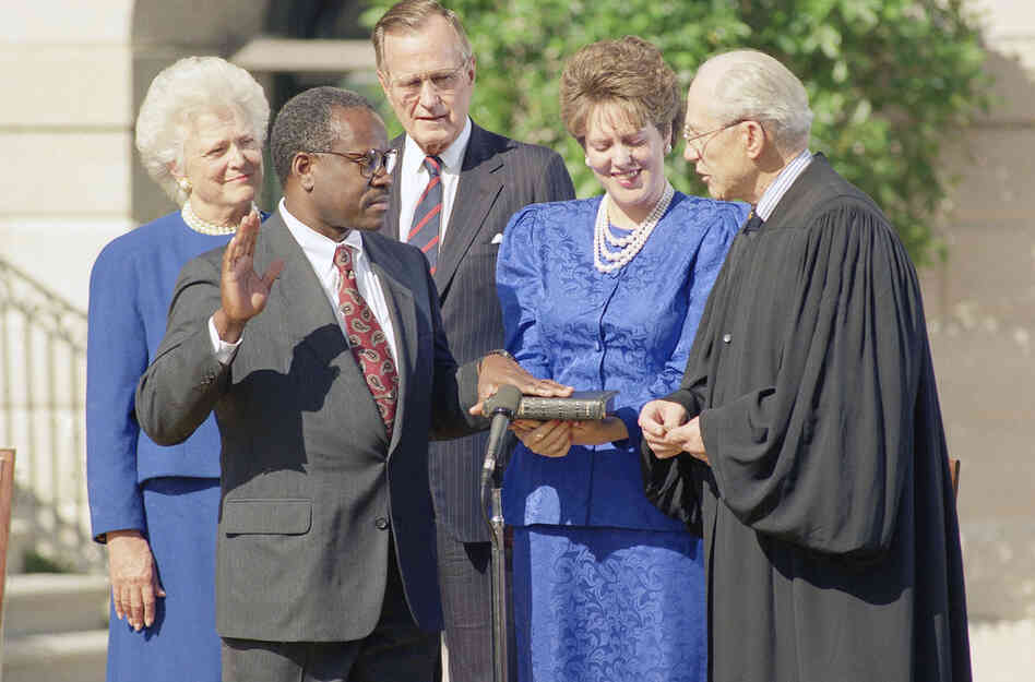 Supreme Court Justice Byron R. White administers the constitutional oath to Thomas in front of President Bush and his wife, Barbara, during a ceremony at the White House on Oct. 19. 