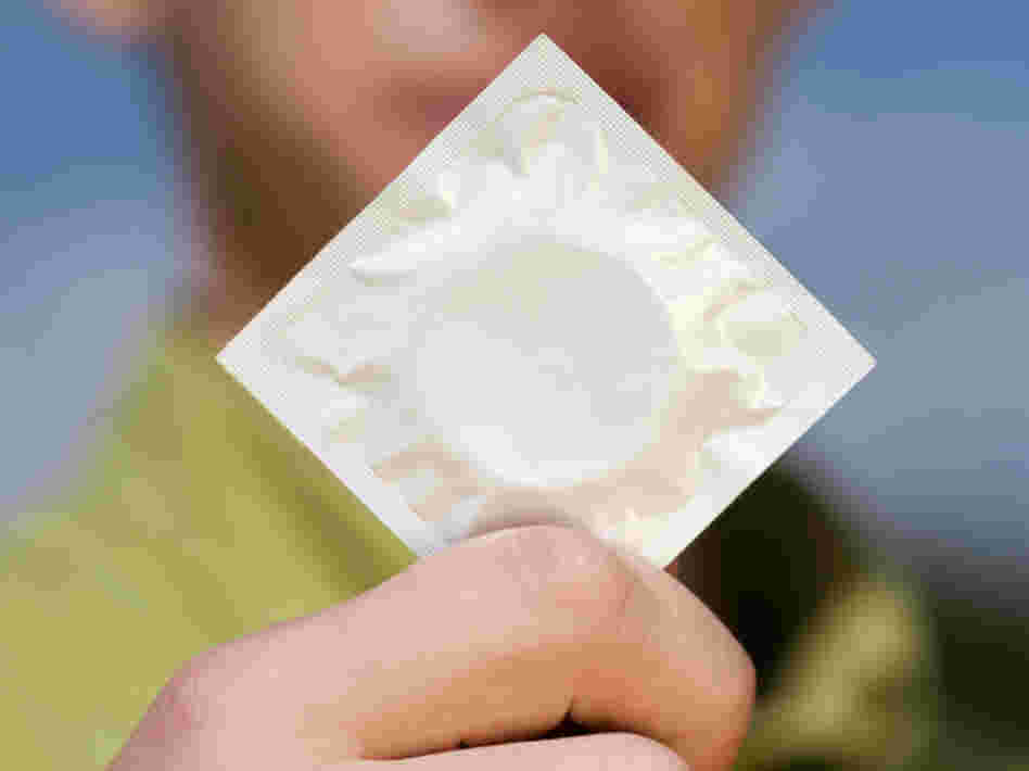 A teenage boy holds a condom. A teenage boy holds a condom.
